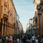 Tłum na zabytkowej ulicy włoskiego miasta z arkadami